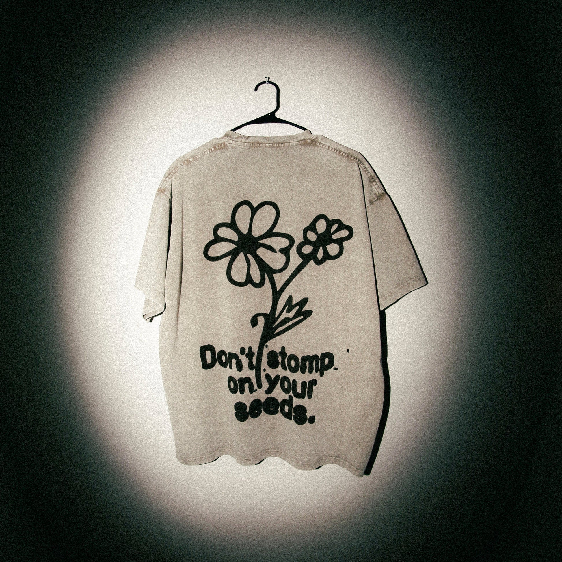 Beige t-shirt with flower design and text on a dark background