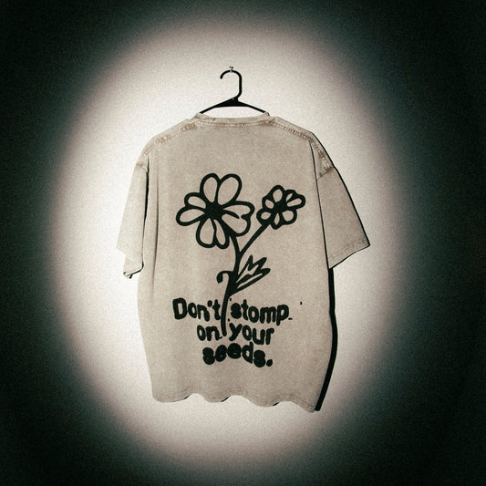 Beige t-shirt with flower design and text on a dark background