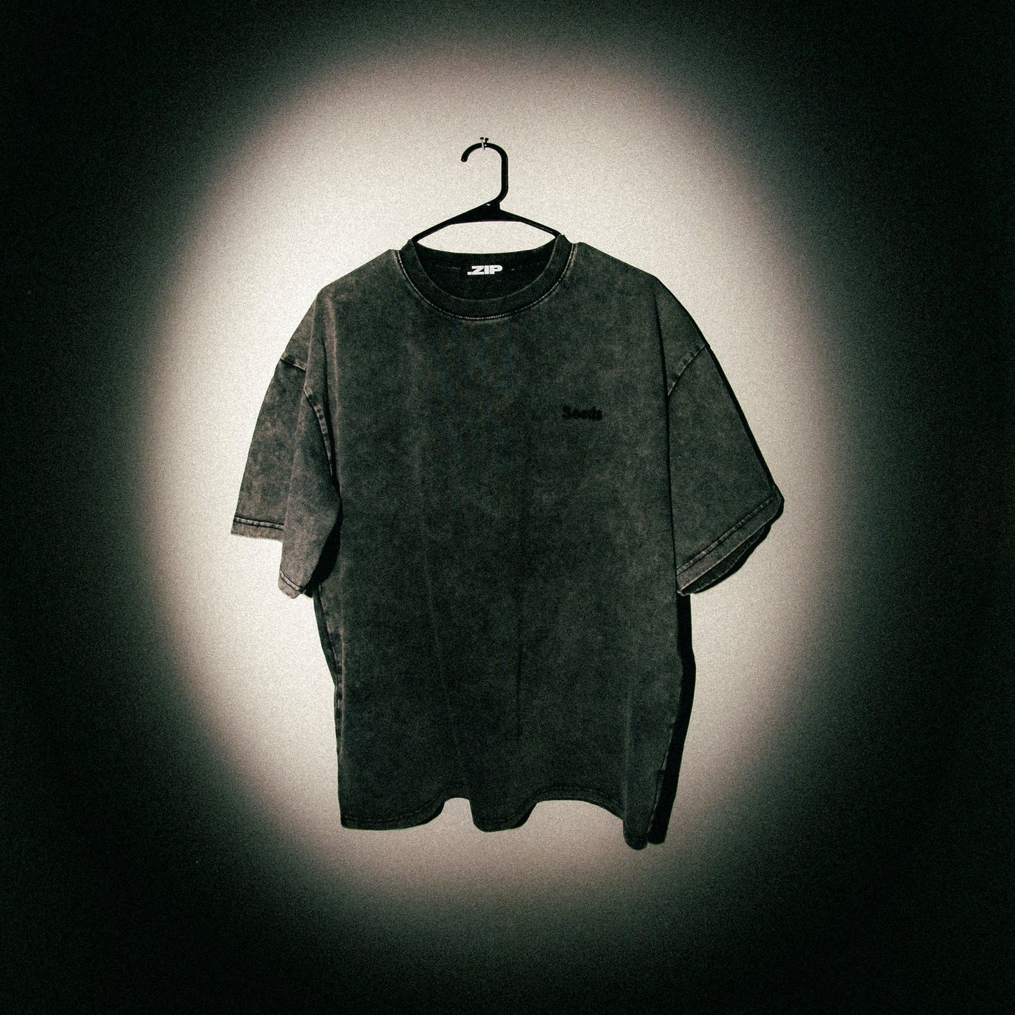 Black t-shirt on a hanger against a dark background